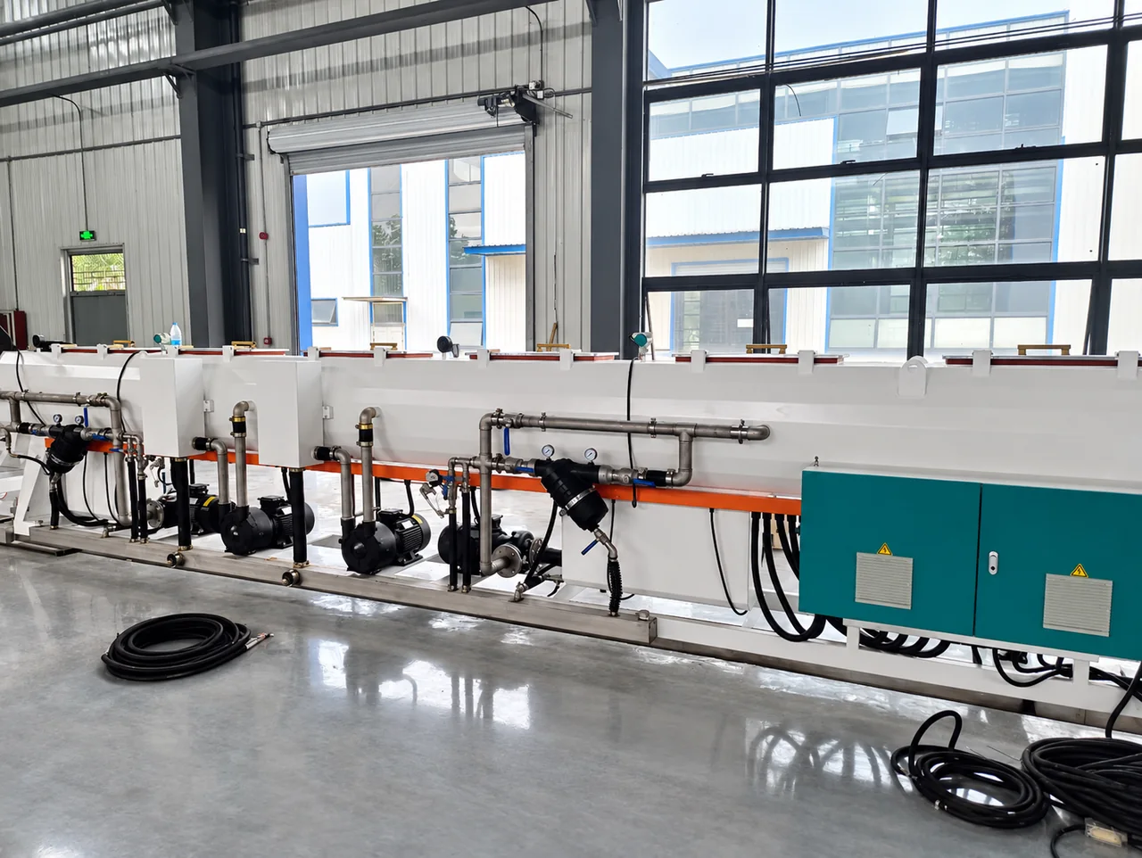 Pipe calibration and cooling tank with pumps and circulation piping in a workshop